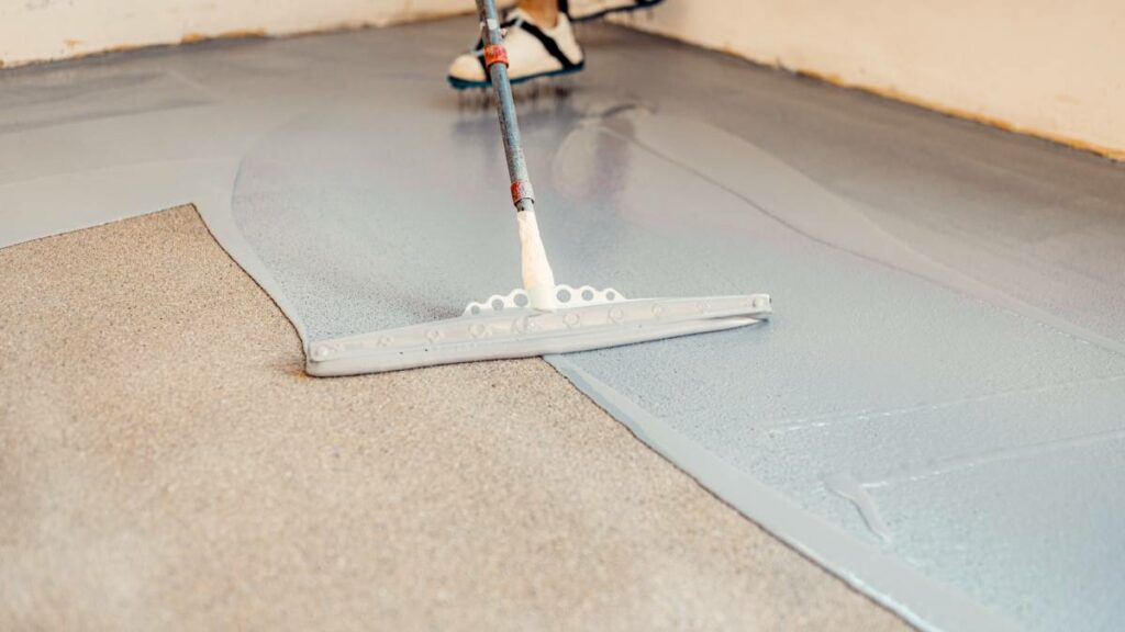 a worker applying epoxy coating on garage floors