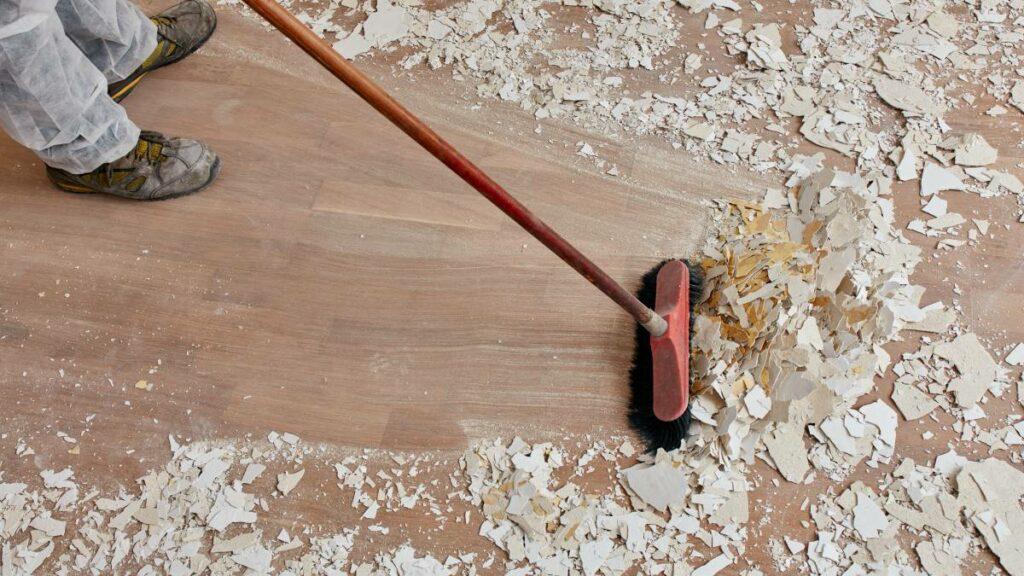 a man sweeping the dust and debris on the floor after construction