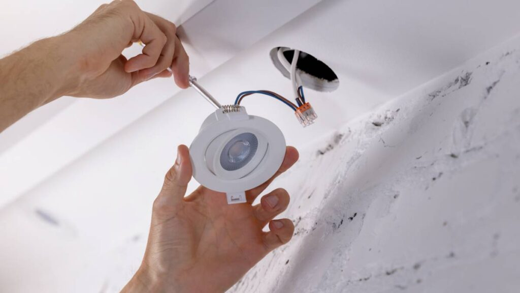 an electrician installing LED downlights on a recessed ceiling