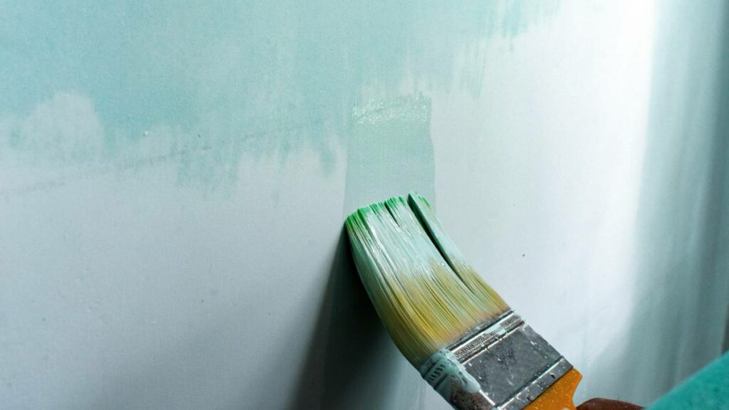 hand painting a wall using a paintbrush