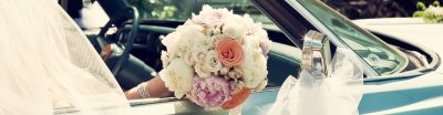 Bride with a flower bouquet in the passenger seat of a vintage wedding car