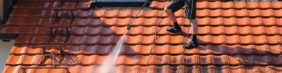 Man on a roof using a high pressure hose