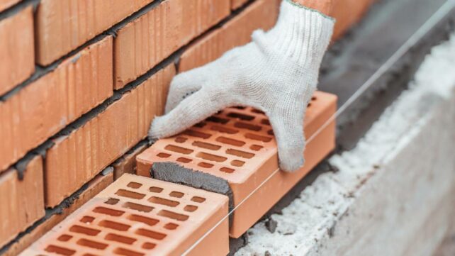 a worker laying bricks as they build a brick wall