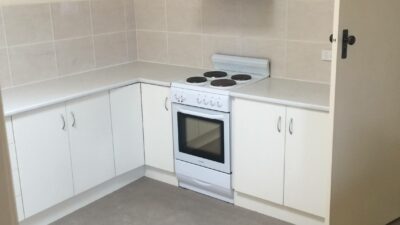 Compact kitchen design featuring a white electric stove and limited counter space. - oven installation cost